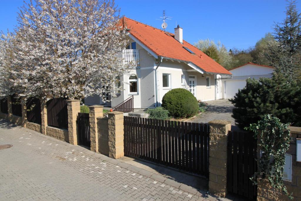 einen Zaun vor einem weißen Haus mit orangefarbenem Dach in der Unterkunft IdyllicPrague Cherry Tree Cottage in Černý Vŭl