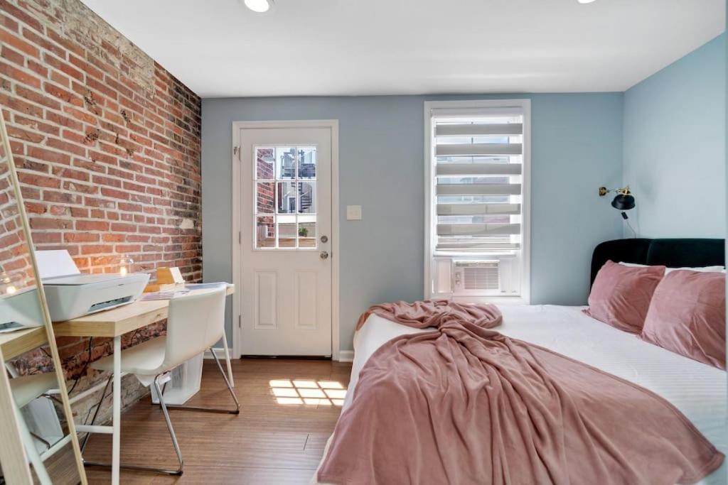 - une chambre avec un lit, un bureau et un mur en briques dans l'établissement Stylish Rowhome-Fishtown-Near Shops, à Philadelphie