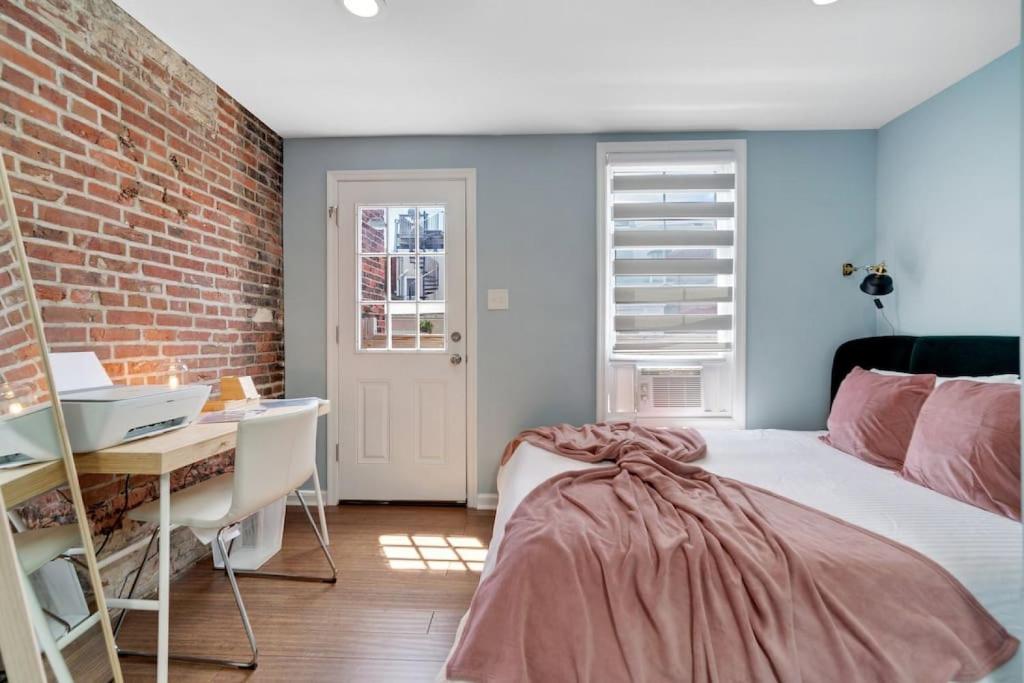 ein Schlafzimmer mit einem Bett, einem Schreibtisch und einer Ziegelwand in der Unterkunft Stylish Rowhome-Fishtown-Near Shops in Philadelphia