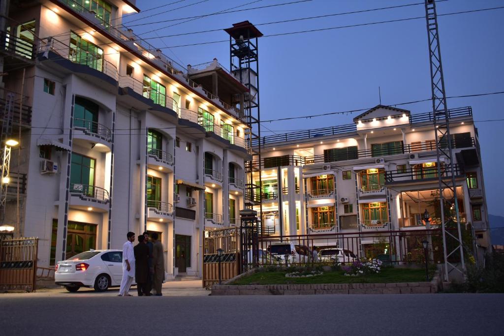 dos personas de pie delante de un edificio por la noche en Swat Hilton Hotel en Swat