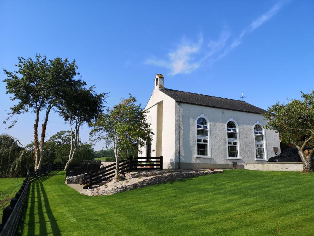 a white church with a grassy yard in front of it at Mullarts Church -The Glendun Apartment in Knocknacarry