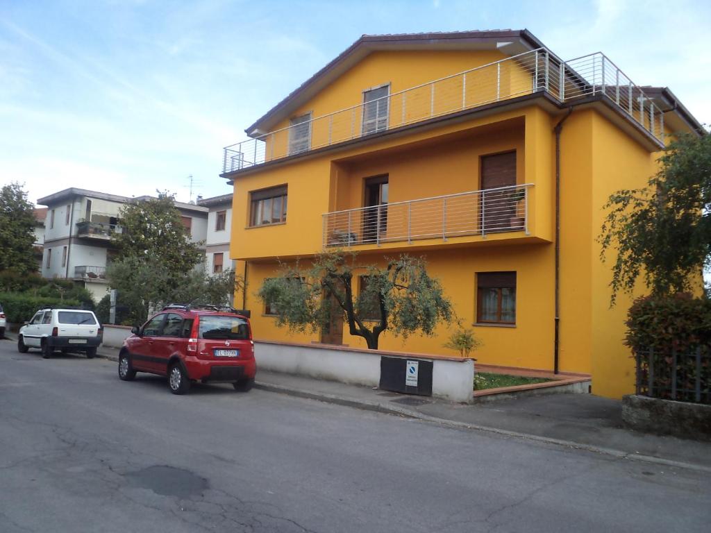 un edificio amarillo con coches estacionados frente a él en Irene, en Pistoia