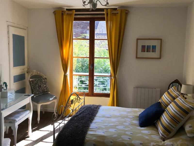 a bedroom with a bed and a desk and a window at Chez Claire in Excideuil