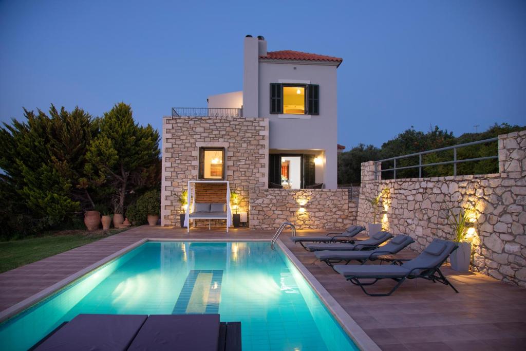 a villa with a swimming pool in front of a house at Geo Villas in Skouloúfia
