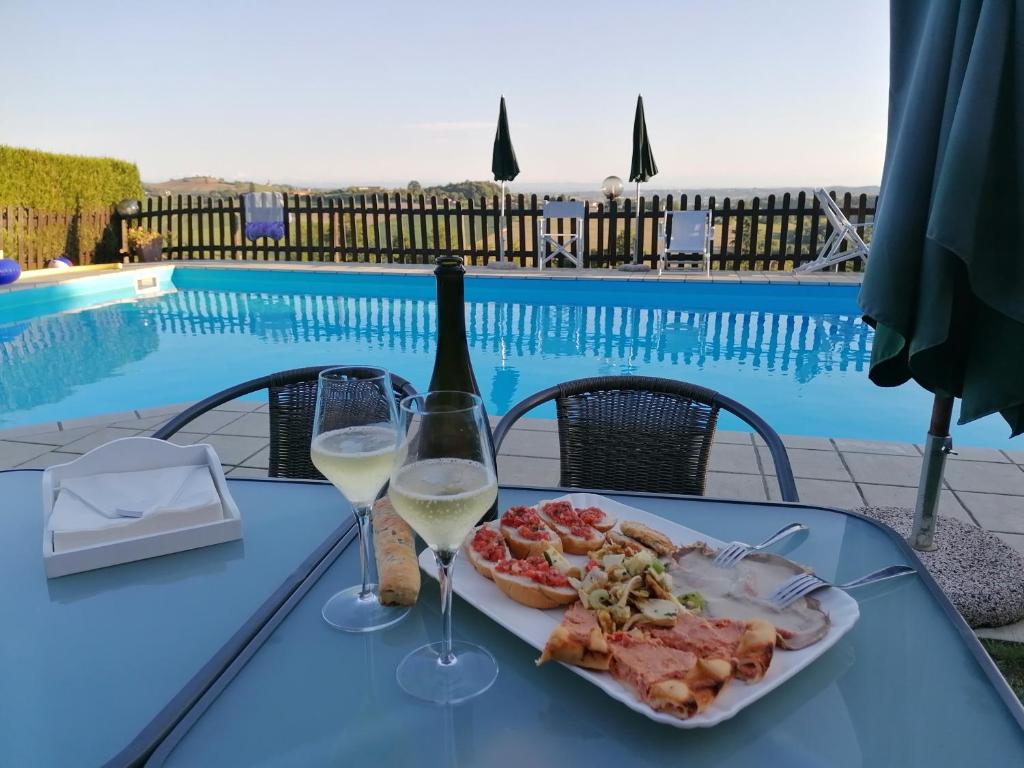 un tavolo con un piatto di cibo e due bicchieri di vino di La Bella Vite a Moncalvo
