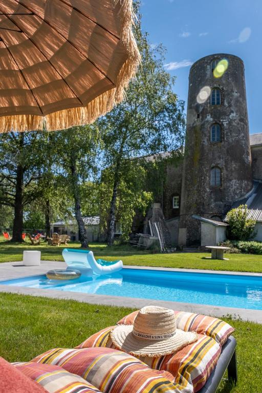 - un chapeau de paille assis sur une chaise près de la piscine dans l'établissement Le Moulin de la Vollerie, à La Tourlandry