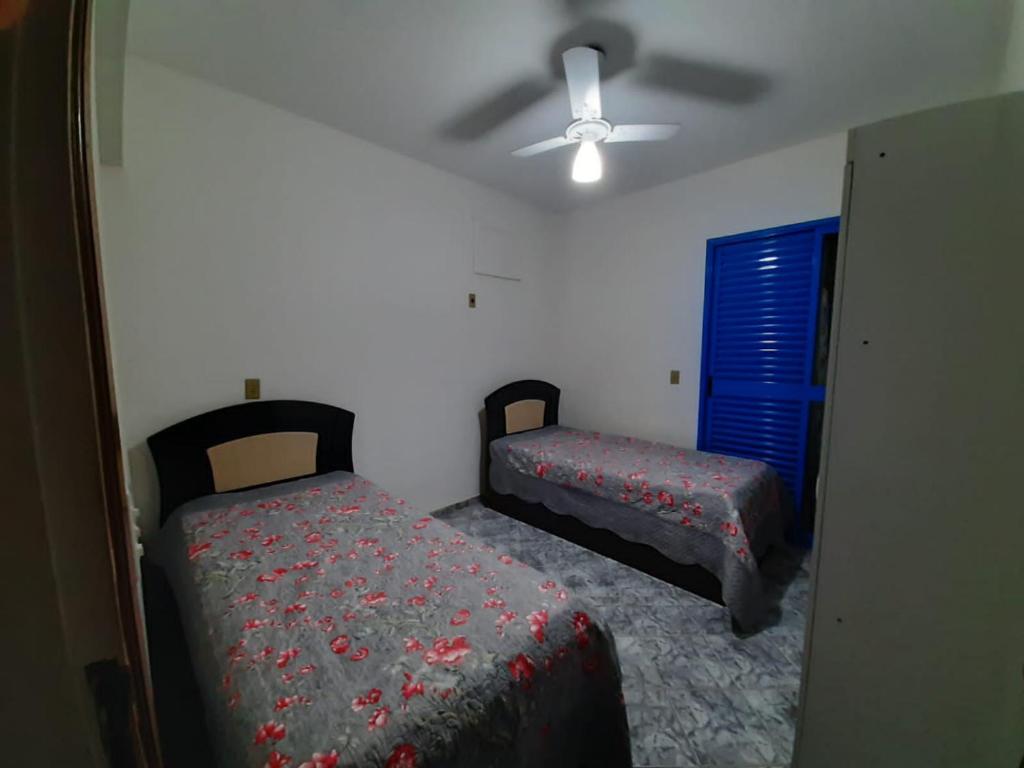 1 Schlafzimmer mit 2 Betten und einem Deckenventilator in der Unterkunft Lindo Apto Praia Martin de Sá em Condomínio com Piscina, Estacionamento, WI-FI 150mbps,PERTO DO MAR!!! in Caraguatatuba