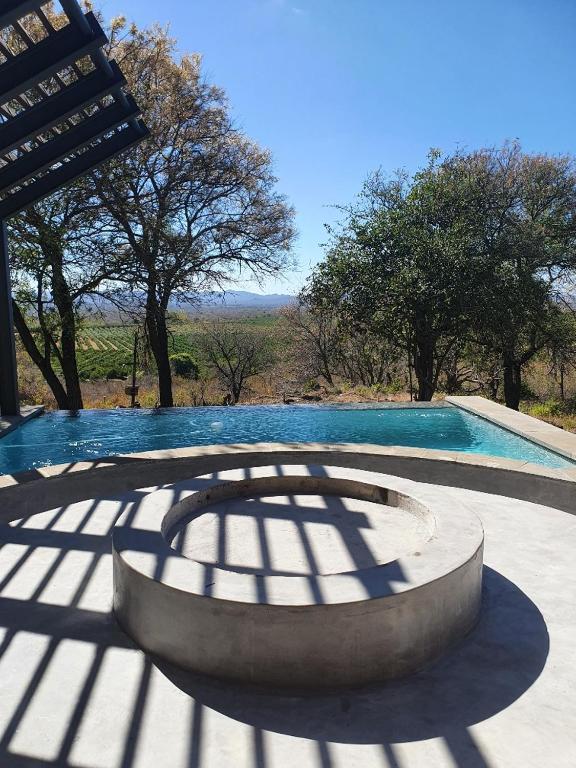 uma sombra de uma piscina com uma mesa e árvores em Via Lactea em Mmafefe