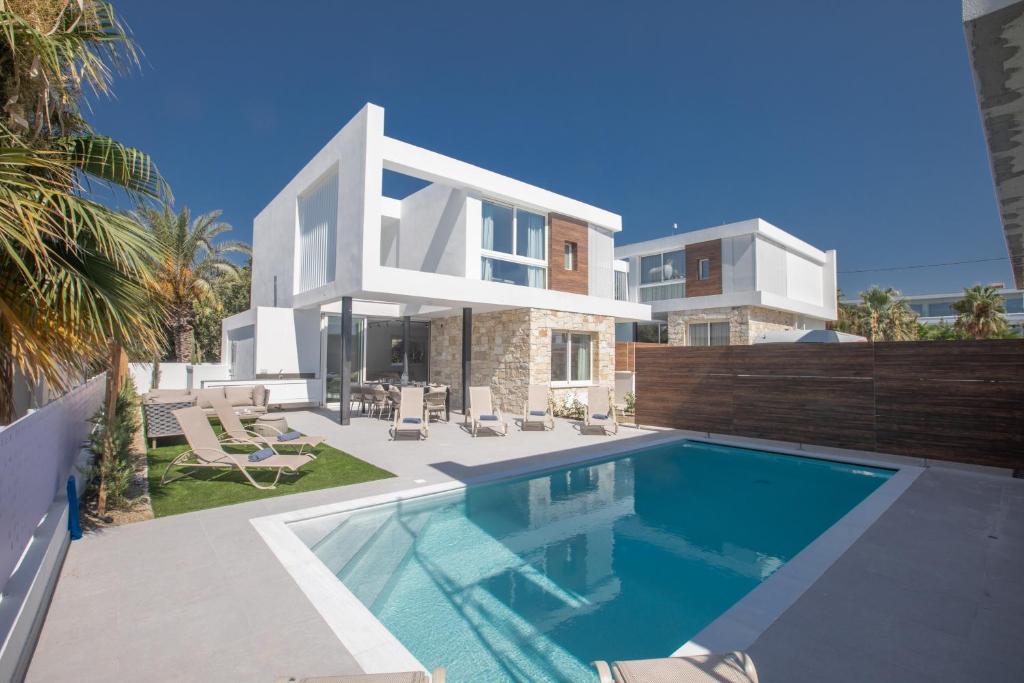 a villa with a swimming pool in front of a house at Kube Luxury Villas in Ayia Napa