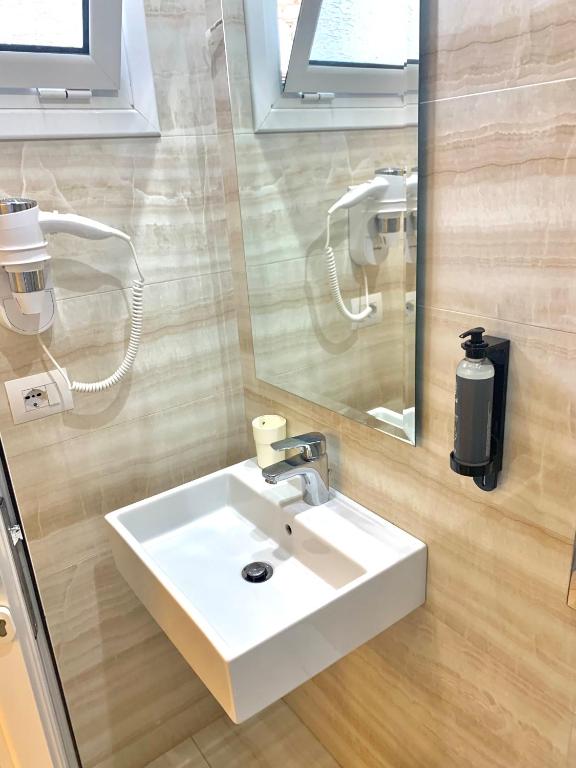 uma casa de banho com um lavatório branco e um espelho. em Hotel Aulona em Sarandë