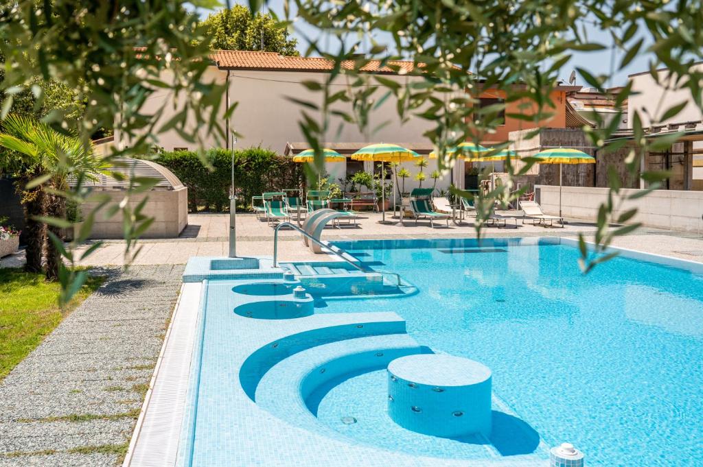 una piscina con sillas y sombrillas en Hotel Terme Posta Padova HOTEL RC12, en Abano Terme