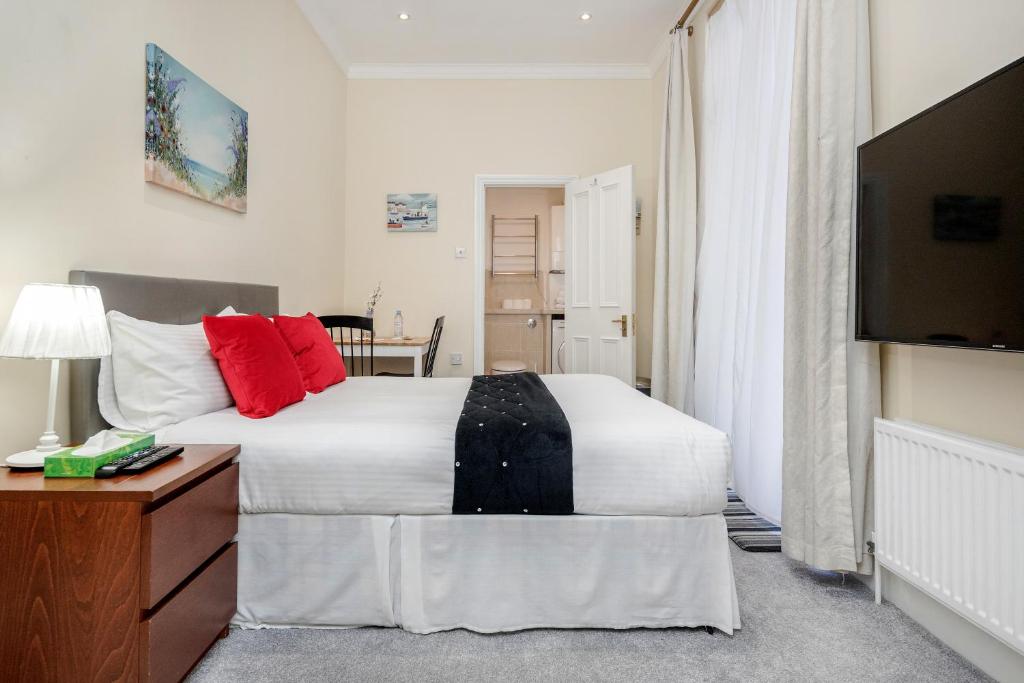 a bedroom with a bed with red pillows and a television at Oxford Street Homestay in London