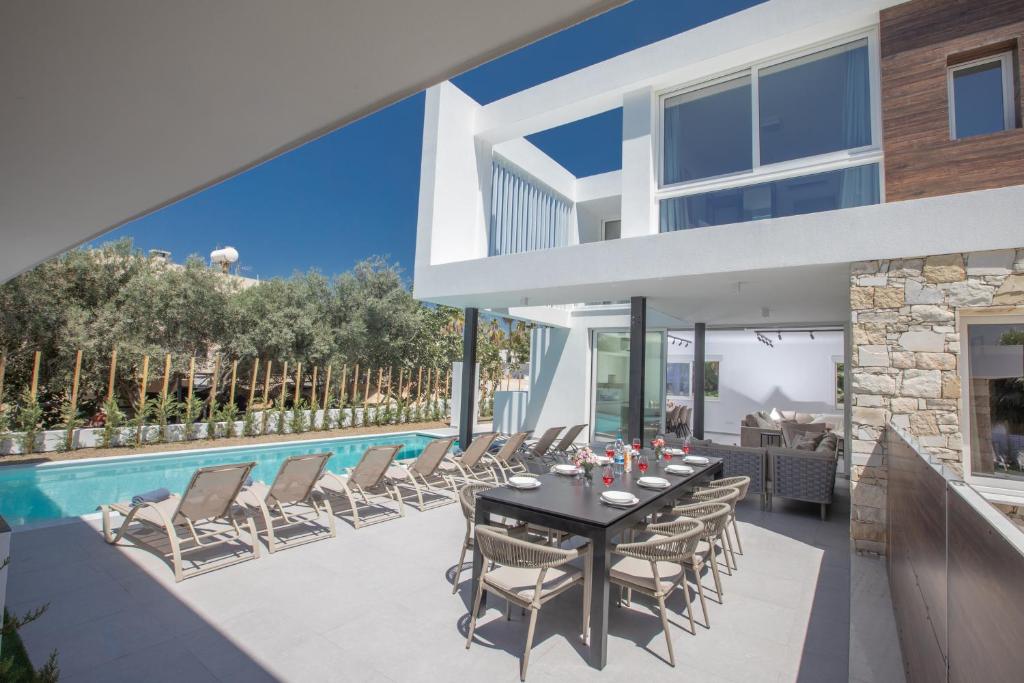 a patio with a table and chairs next to a pool at Kube Luxury Villas in Ayia Napa