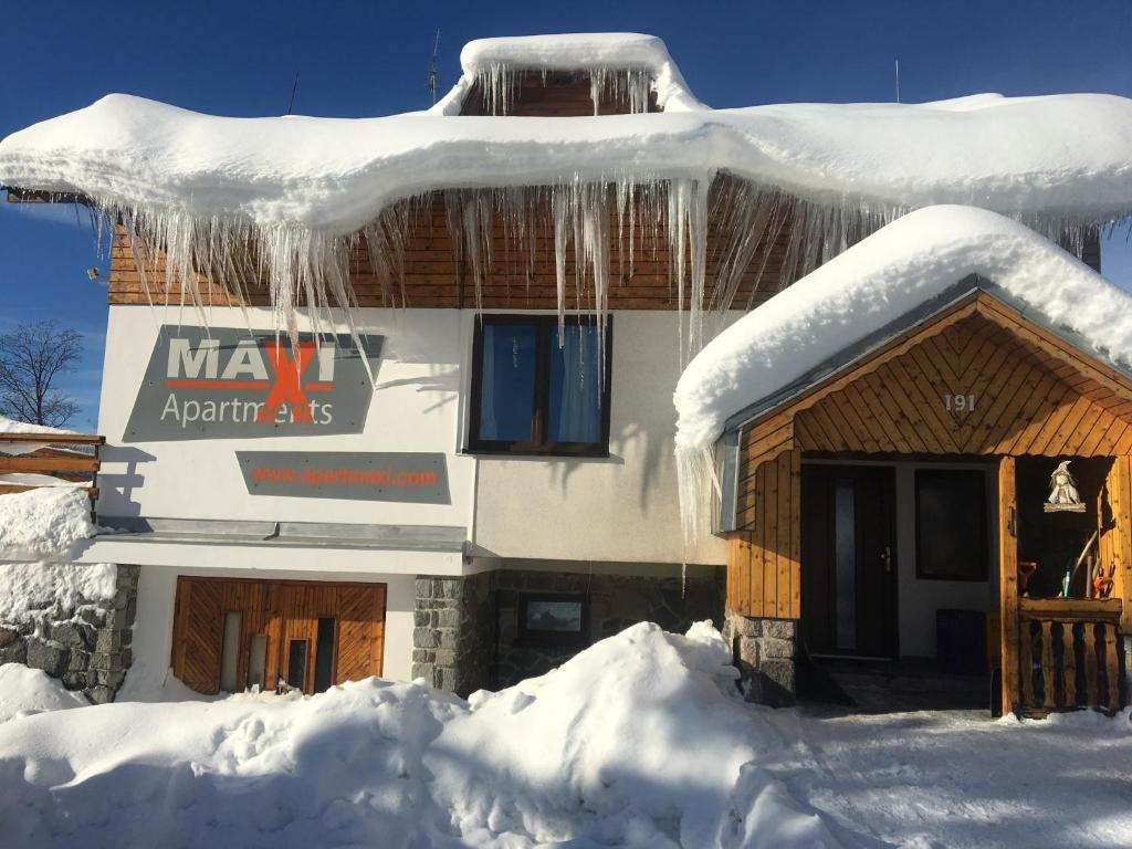 a building covered in snow with icicles hanging from it at Apartments Maxi in Strážné