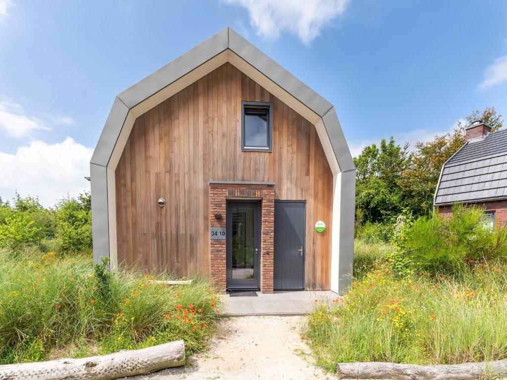een klein houten huis met een schuin dak bij Beautiful villa with sauna near the sea in Egmond aan den Hoef