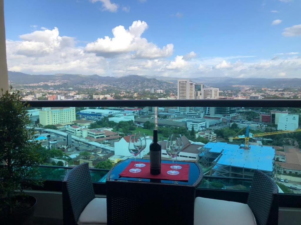 Una botella de vino sentada en una mesa en un balcón en JF Three Bedroom Apartment, en Tegucigalpa