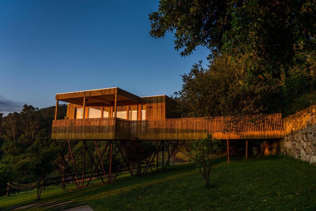 ein Haus mit einem Holzdach auf einem Grasfeld in der Unterkunft Cabanas de Canduas in Cabana de Bergantiños