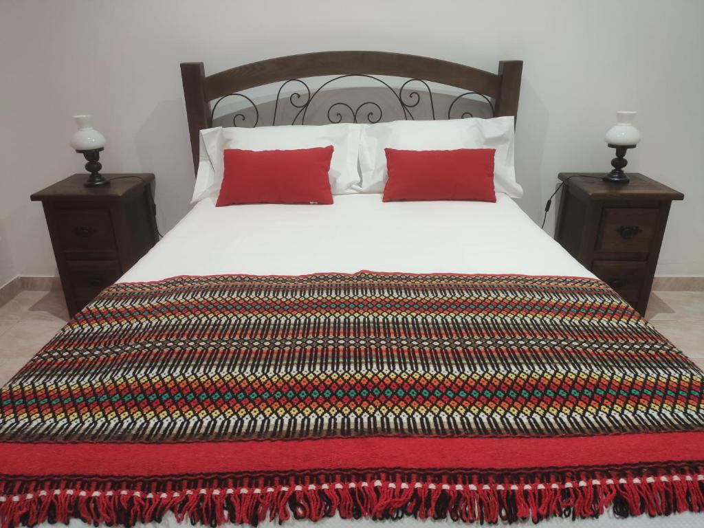 un letto con cuscini rossi e 2 comodini di AL Colmeia de Mel a Reguengos de Monsaraz