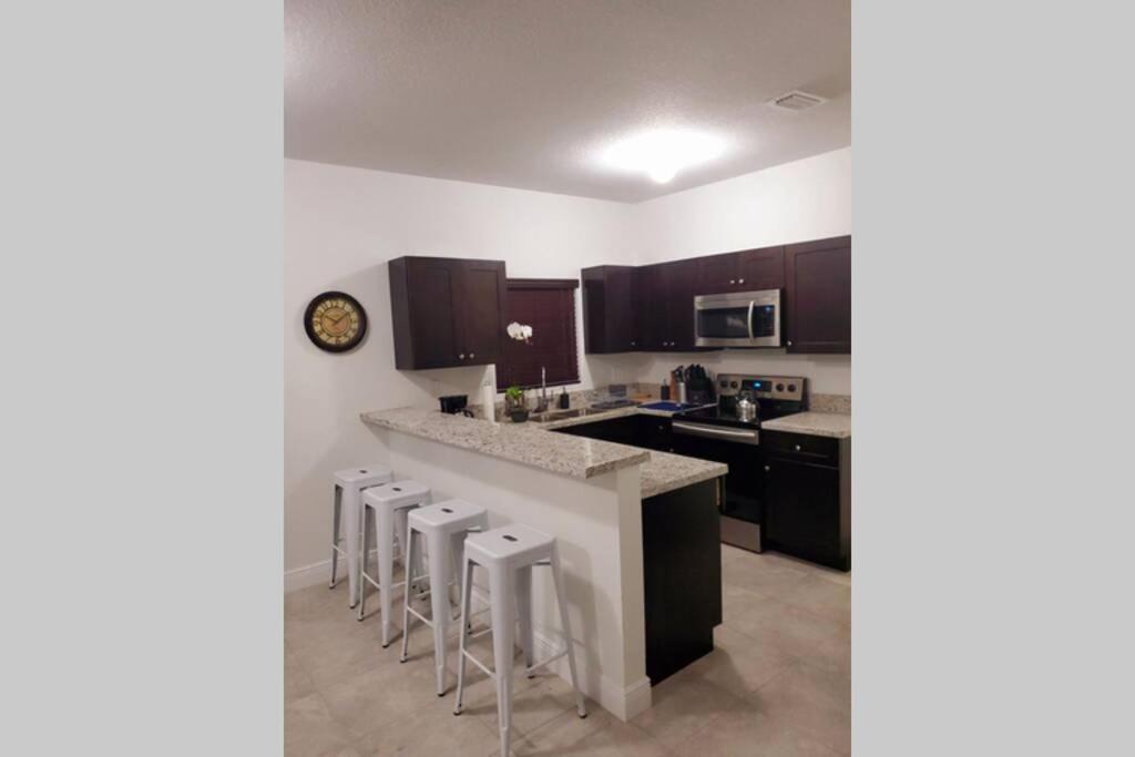 a kitchen with a counter and bar stools at New house on the block near Miami Airport. in Miami