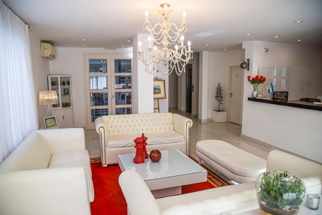 a living room with white furniture and a chandelier at Sorrento Hotel Boutique in Trenque Lauquen