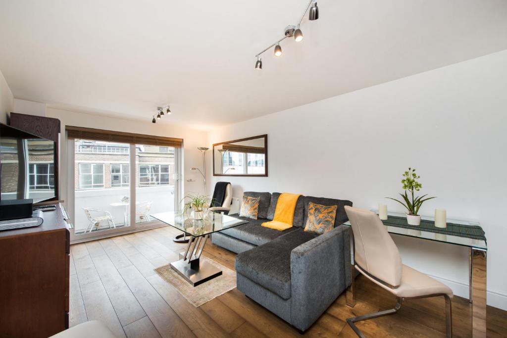 uma sala de estar com um sofá e uma mesa de vidro em Views For Days - Fitzrovia - by Frankie Says em Londres