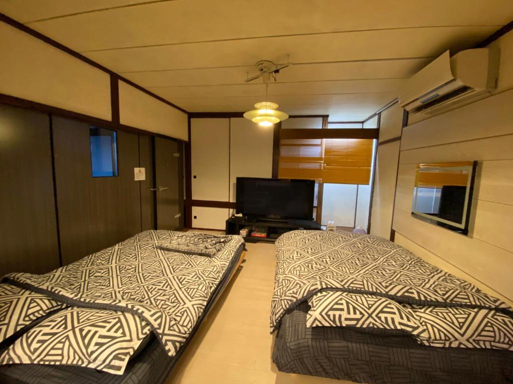 two beds in a room with a flat screen tv at 札幌ドーム前ハウス Sapporodome front house in Sapporo