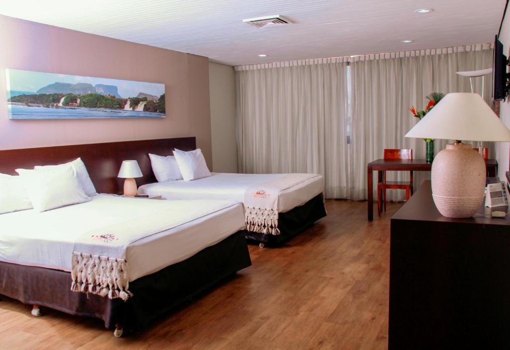 Habitación de hotel con 2 camas y mesa en Hotel CCT Caracas, en Caracas