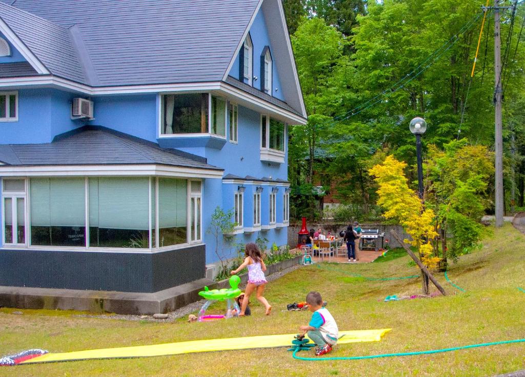 two children playing with kites in the yard of a house at Maple Chalet Hakuba in Hakuba