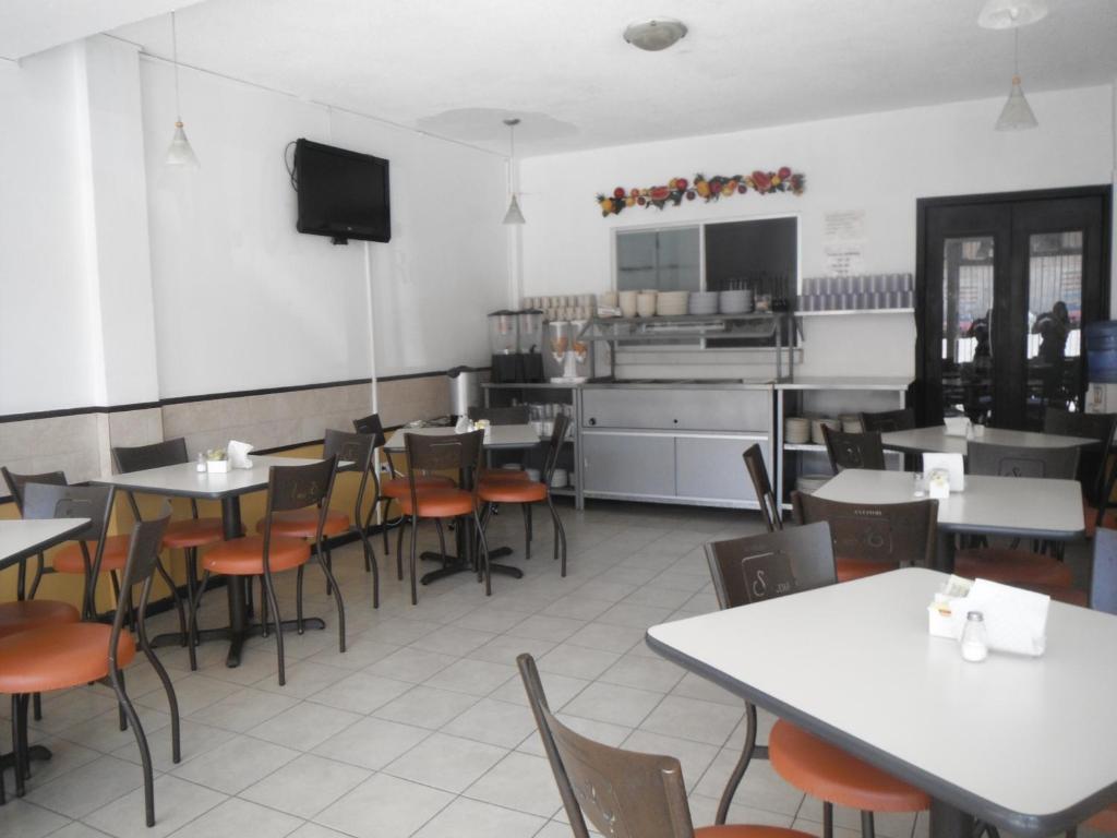 un restaurante con mesas y sillas y una cocina en Hotel Santa Cruz, en Chihuahua