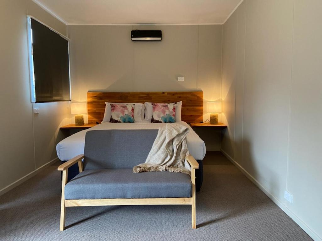 um quarto com uma cama e uma cadeira em The Railway Hotel em Queenstown