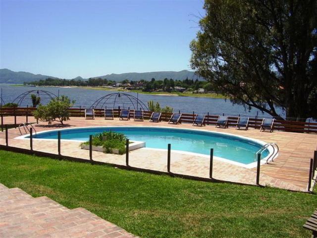 a swimming pool next to a body of water at Aguada Chica Bungalows in Villa Carlos Paz