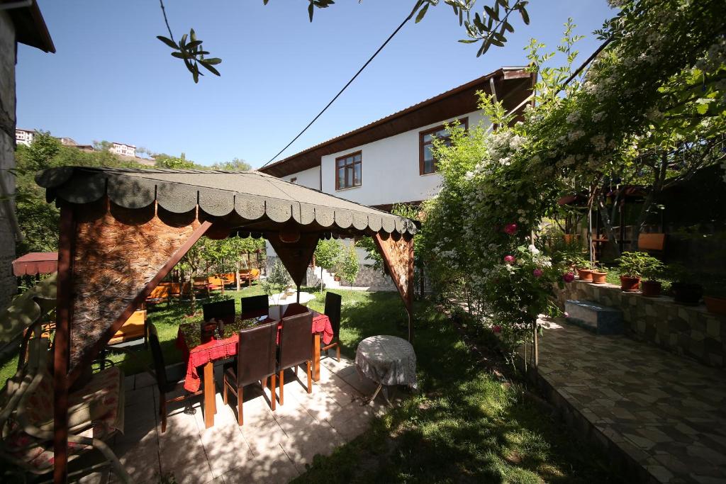 un jardín con mesa y sillas bajo una pérgola en Emiroğlu Konak Otel en Safranbolu