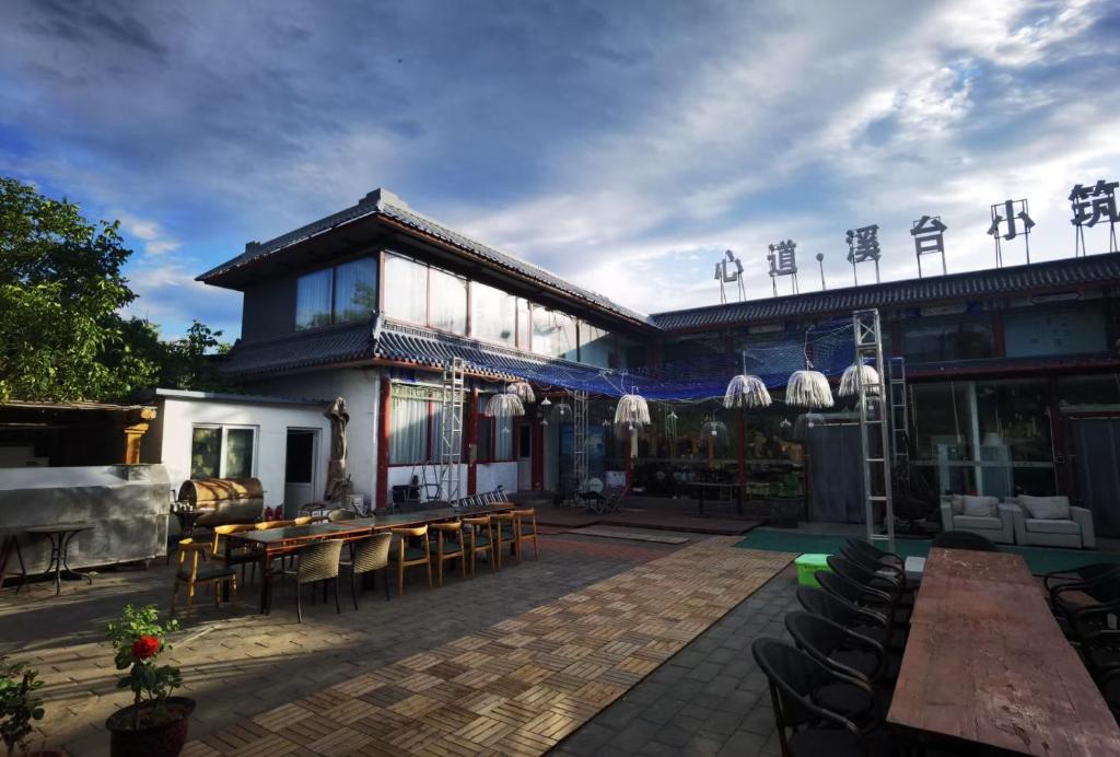 Xindao Xitai Xiaozhu Hotel في Huangkan: مبنى به فناء به طاولات وكراسي