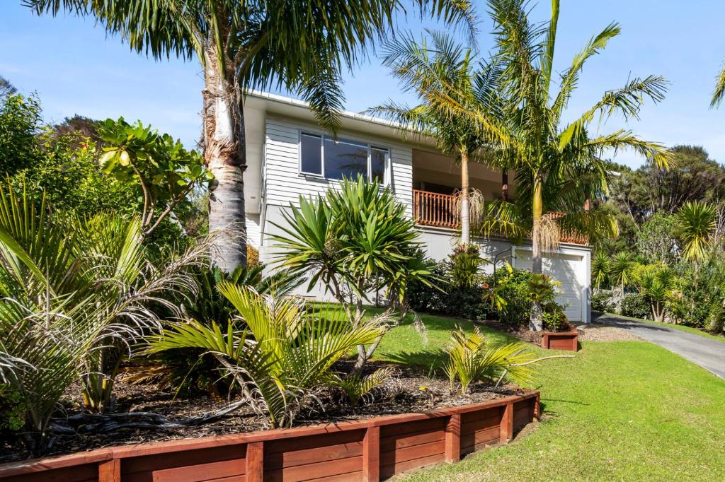 ein Haus mit Palmen davor in der Unterkunft Ota Point Paradise - Whangaroa Holiday Home in Whangaroa