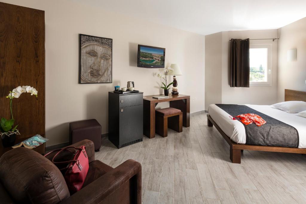 Habitación de hotel con cama y sofá en Le Ya'Tis en Saint-Laurent-des-Arbres