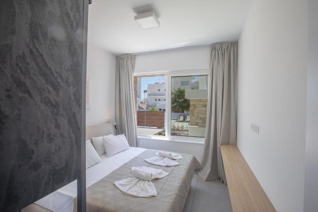 a bedroom with a bed and a large window at Kube Luxury Villas in Ayia Napa
