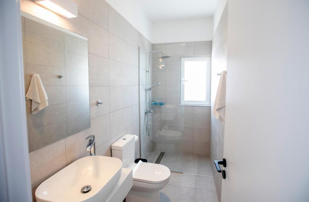a white bathroom with a toilet and a sink at Kube Luxury Villas in Ayia Napa
