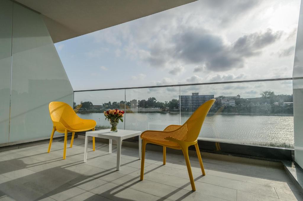 twee stoelen en een tafel op een balkon met uitzicht op het water bij Mirage Beach Spa Hotel in Eforie Nord