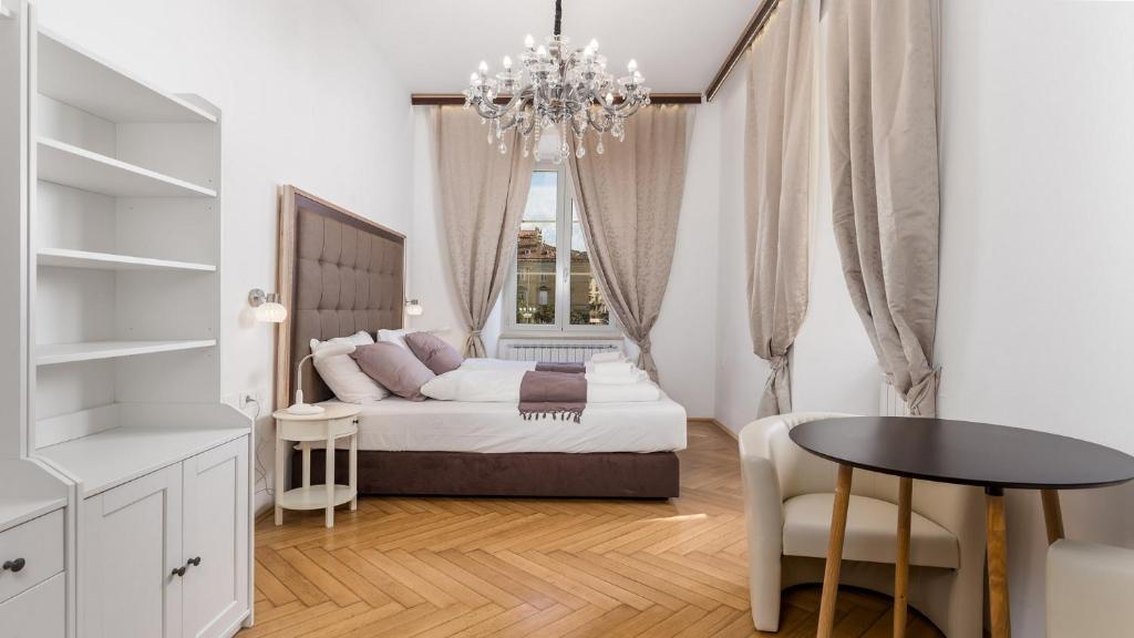een slaapkamer met een bed, een tafel en een kroonluchter bij Apartments ART TEATRO in Rijeka