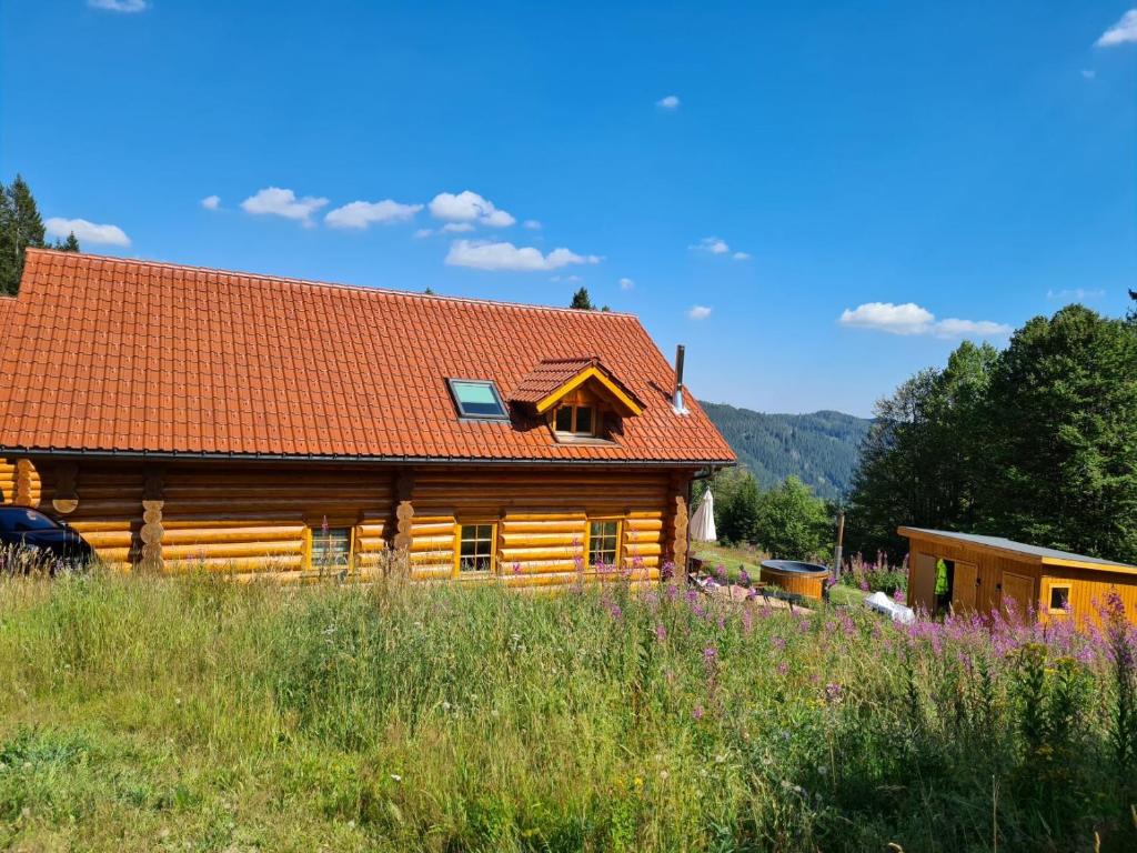uma cabana de madeira com um telhado vermelho em Luxus-Ferienhaus Blockhaus Chalet Nr 2 Toplage am Feldberg mit Sauna, Outdoor-Hottub, Kamin auf 1300m üM em Feldberg