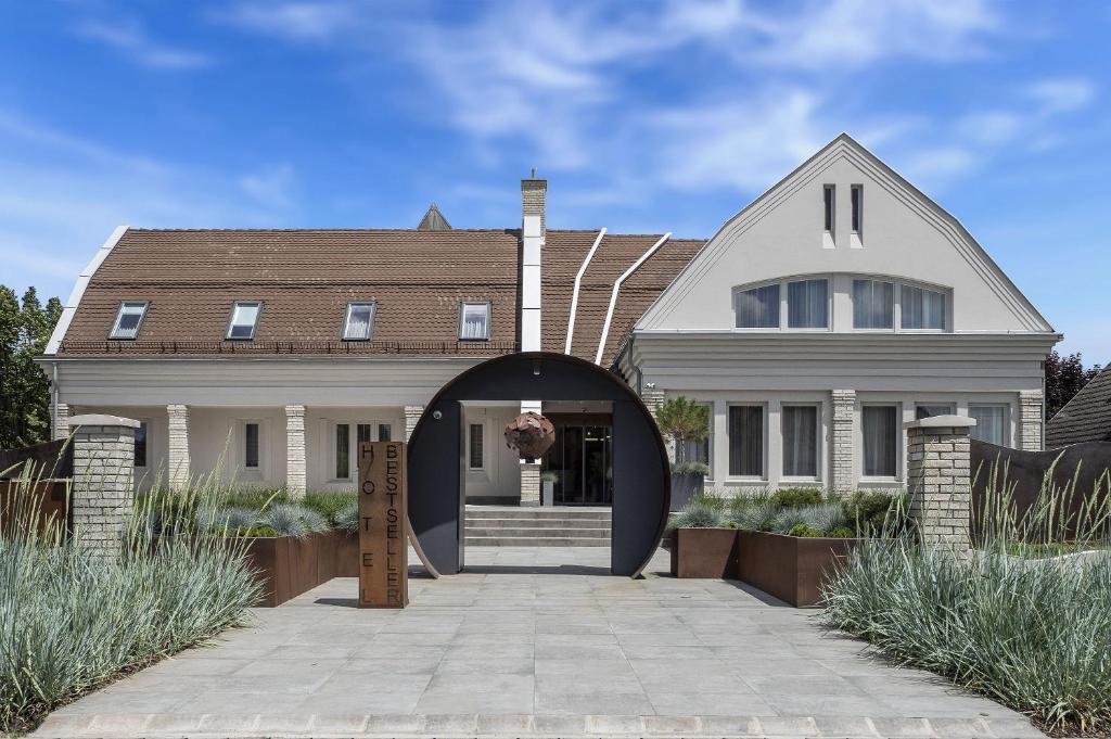 Una gran casa blanca con una entrada arqueada en Hotel Bestseller en Kecskemét