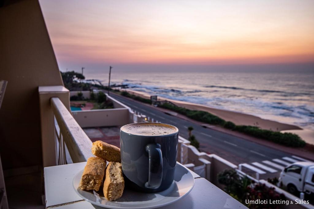 a cup of coffee on a table next to the ocean at 8 Waterfront in Umdloti
