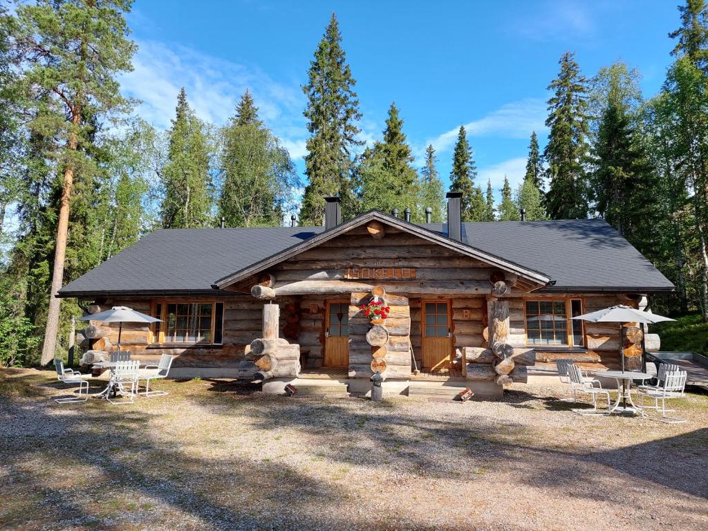 a log cabin with tables and chairs in front of it at Isokelo Log Apartments in Salla