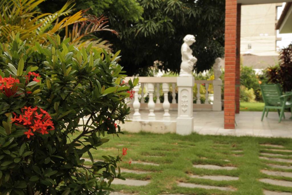 a white fence with a statue in a yard at Hotel Jardim in Fortaleza