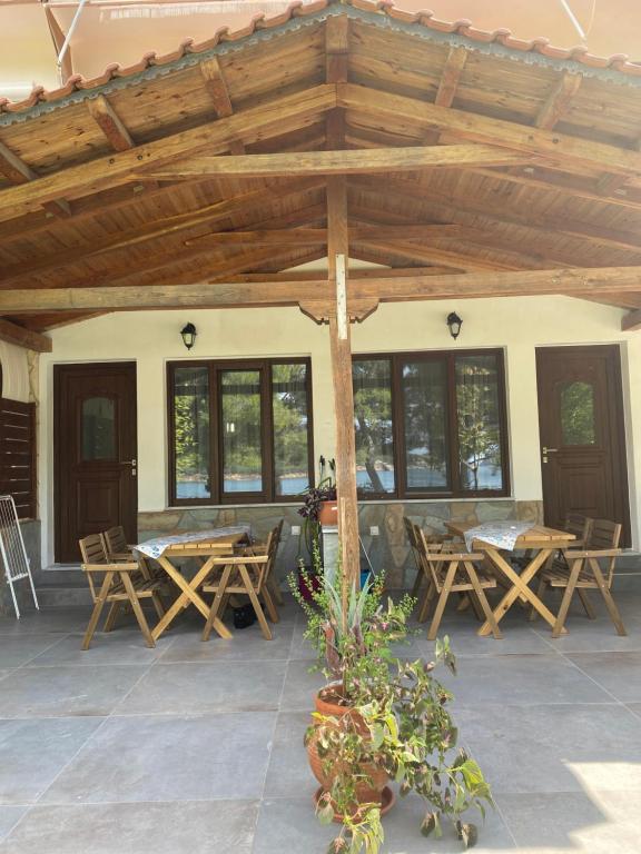 un pabellón de madera con mesas y sillas en un patio en Pinelopi’s House, en Porto Koufo