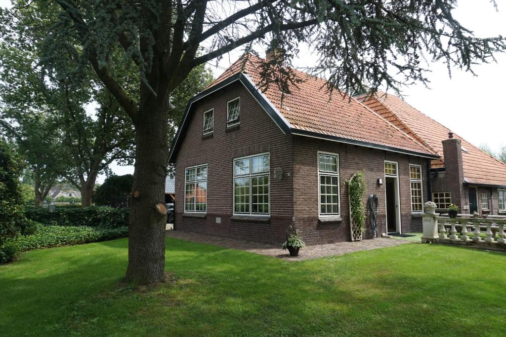a brown brick house with a tree in the yard at Charmantbuiten in Zandhuizen