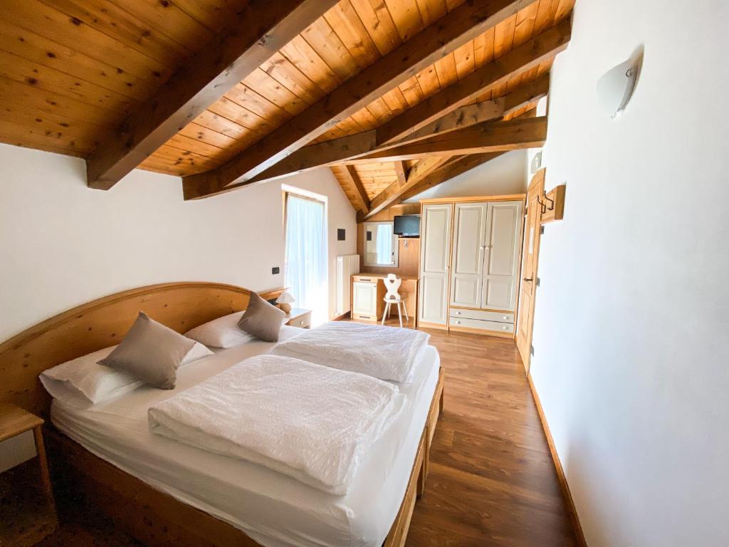 a bedroom with a large bed in a room with wooden ceilings at Hotel Canterbury in Castello Tesino