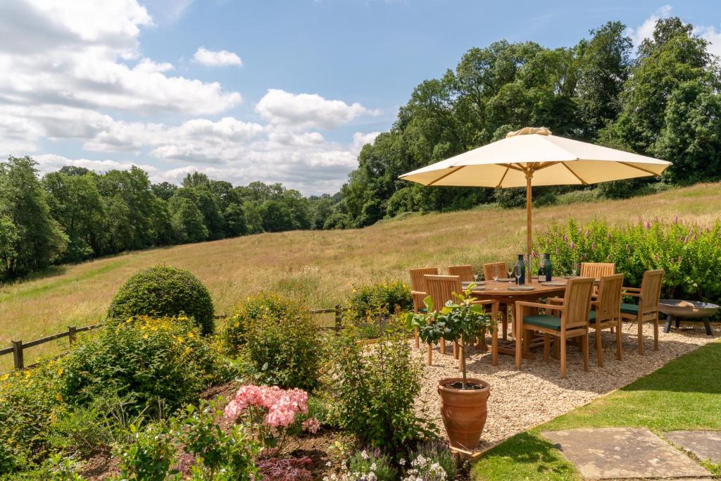einen Tisch mit einem Sonnenschirm im Garten in der Unterkunft Court Cottage in Stroud