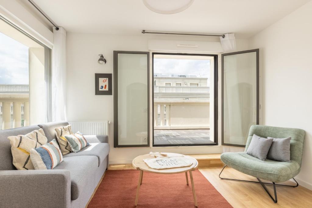 een woonkamer met een bank, een stoel en een tafel bij Edgar Suites Levallois – Jules Verne in Levallois-Perret