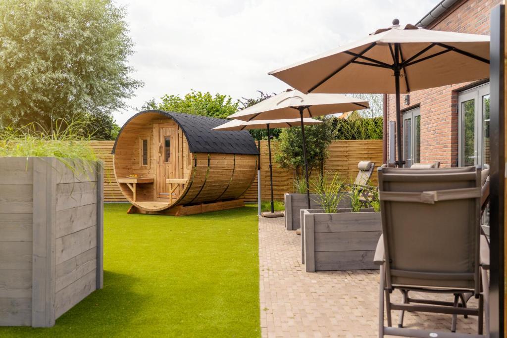 un jardin avec une cabane dans les arbres et un parasol dans l'établissement Naturisme B&B Ilmatar, clothing optional, à Deerlijk